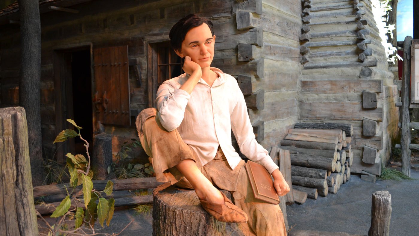 young Abraham Lincoln is depicted outside his boyhood log cabin at the Abraham Lincoln Presidential Library and Museum