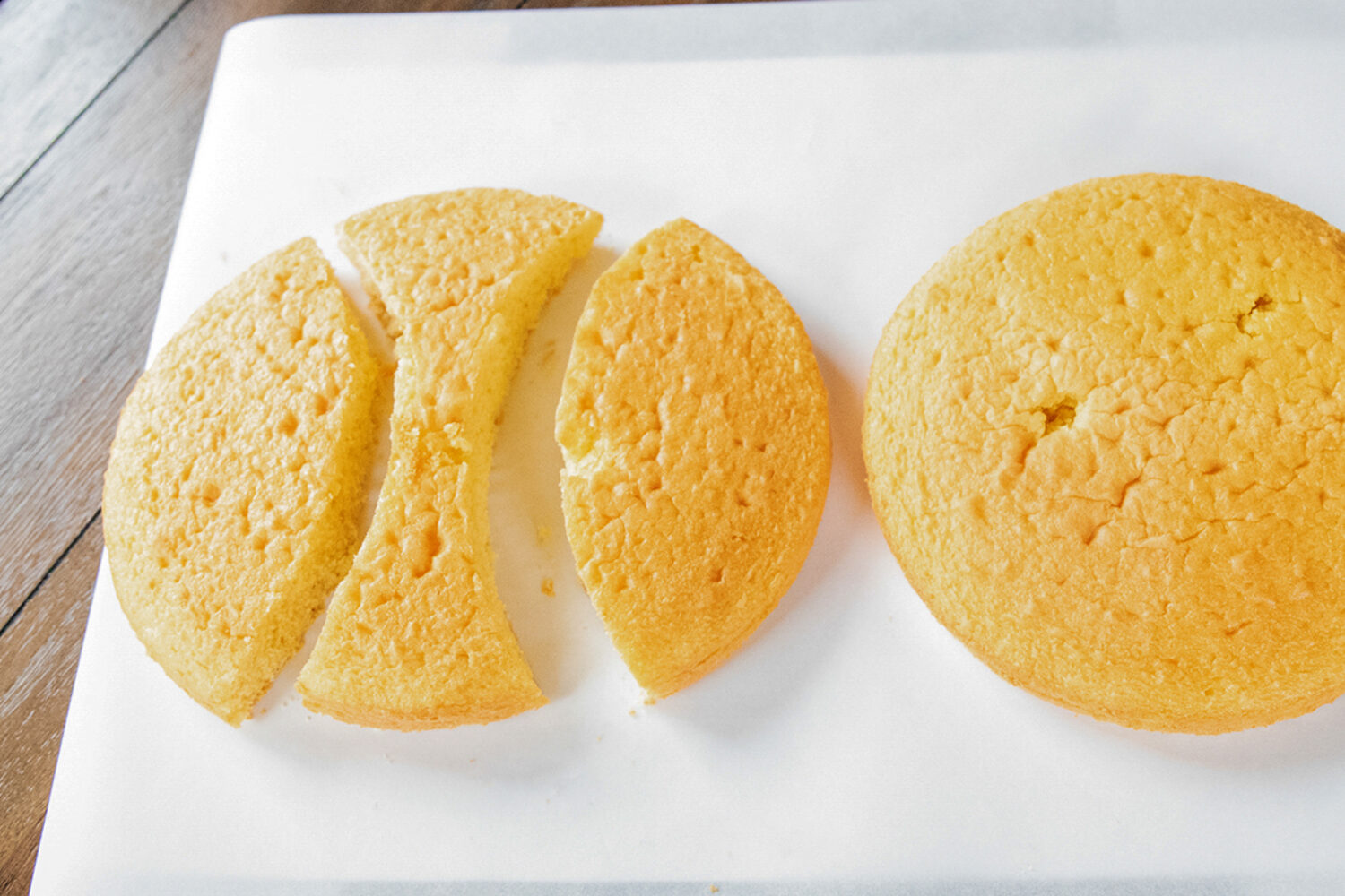 Two round cakes, with one cut into unusual shapes