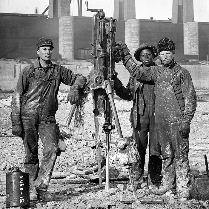 Laborers pose next to a compressed-air rock drill during the construction of the Chicago Sanitary and Ship Canal