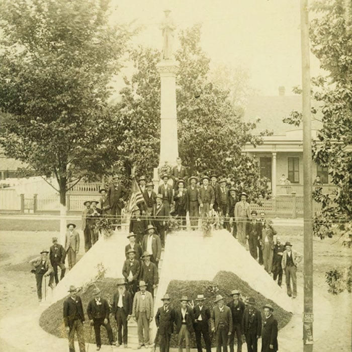 Confederate soldiers pose with a Confederate monument