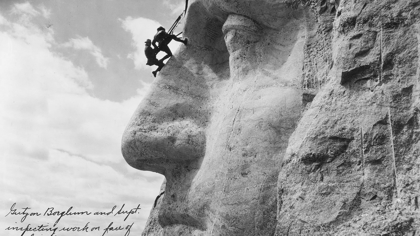 Gutzon Borglum and a superintendent inspecting work on the face of George Washington on Mount Rushmore