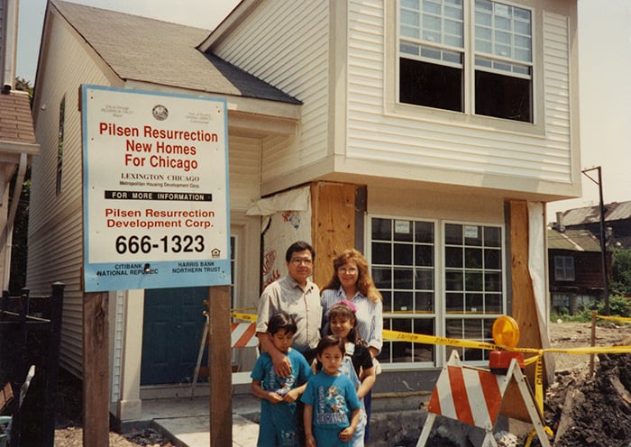 A family stands in front of their new home on Throop