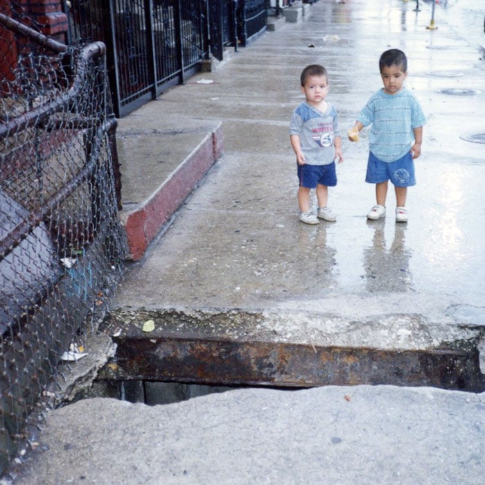 Two children by vaulted sidewalk with hole