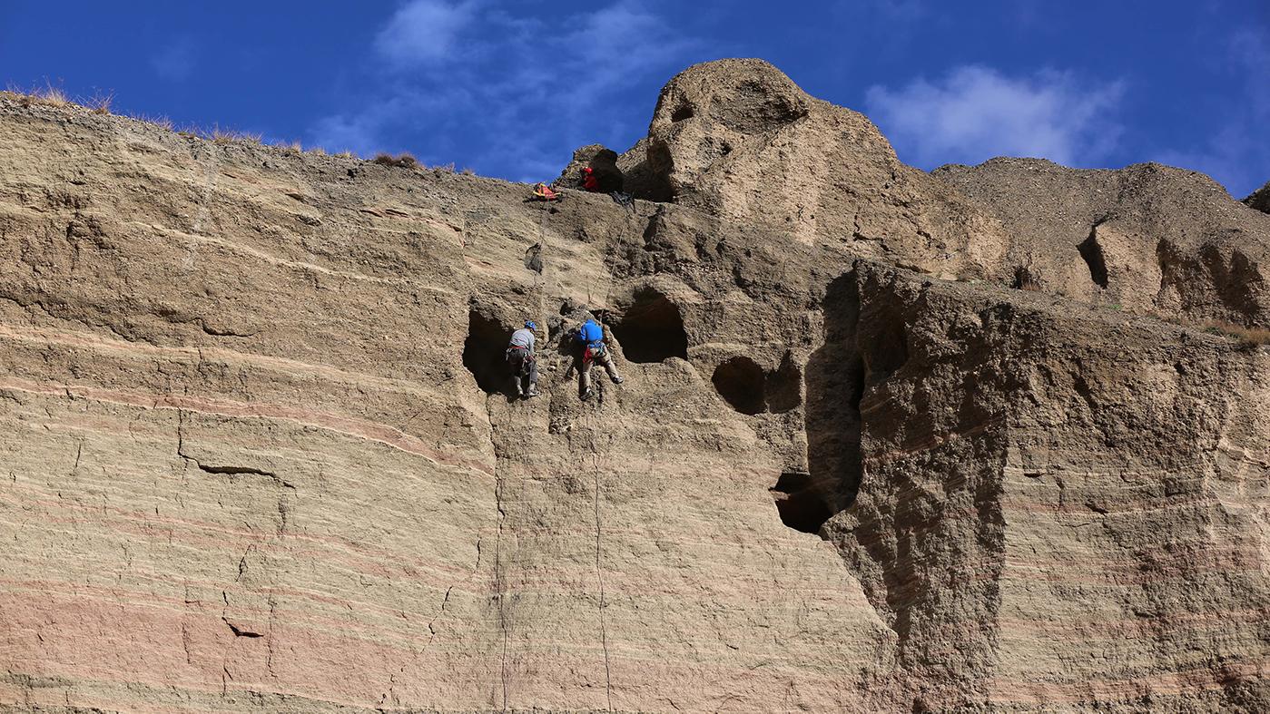 Climbers Pete Athans and Jake Norton excavating and photographing the Samdzong Sky Tombs, Upper Mustang, Nepal. Photo: Liesl Clark