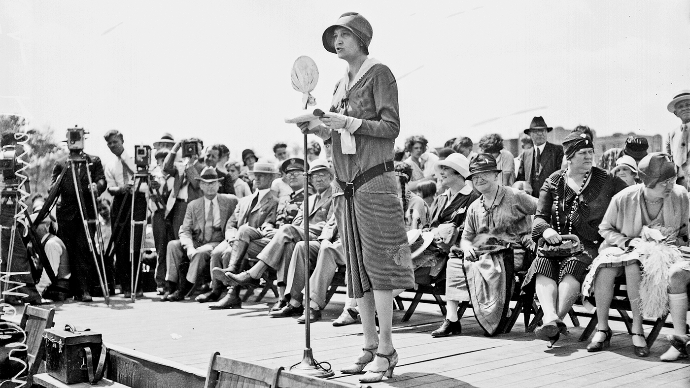 Politician Ruth Hanna McCormick, U.S. Representative from Illinois at-large from 1929-1931, standing on an outdoor stage in Chicago, Illinois, 1929. Cameramen standing behind cameras mounted on tripods are visible in the background.