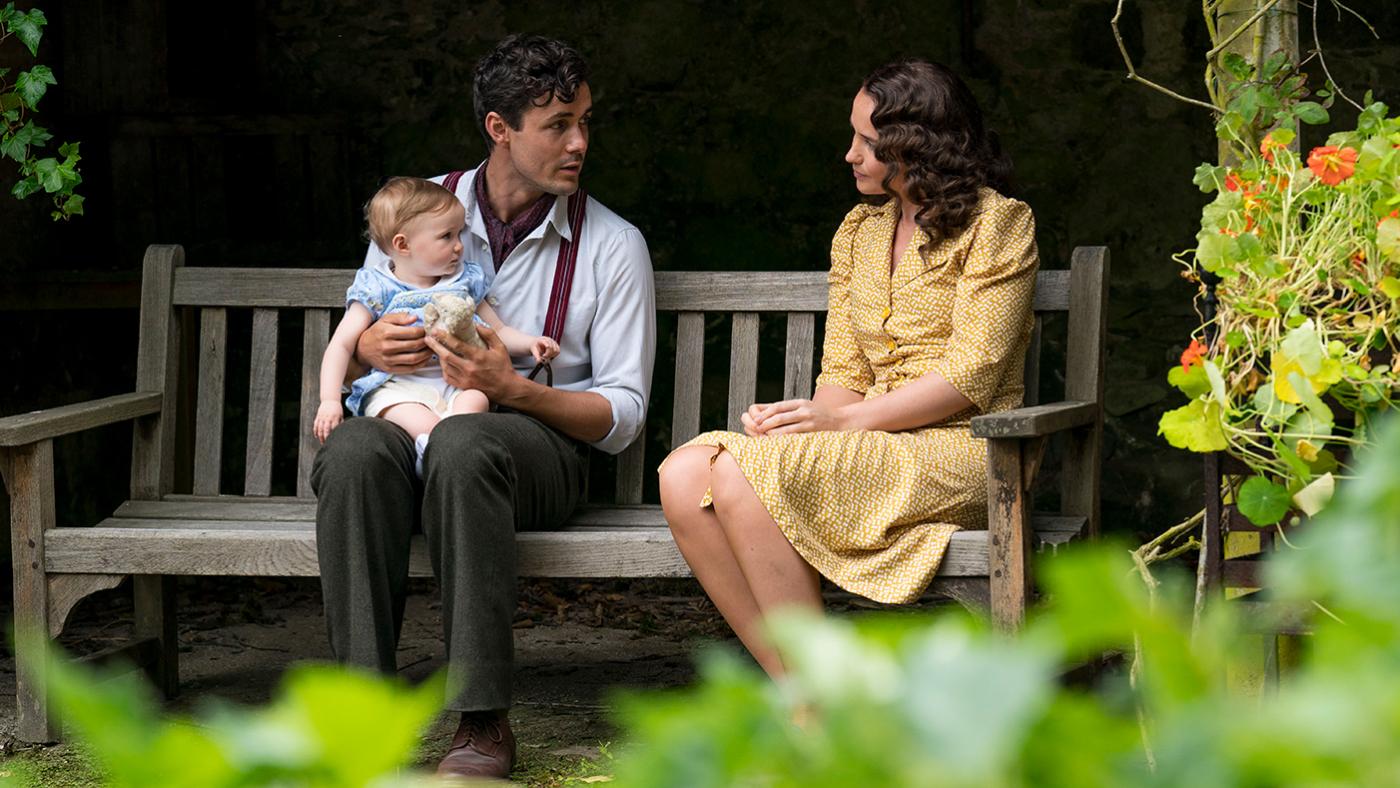 Harry sits with Vera on his lap on a bench next to Lois