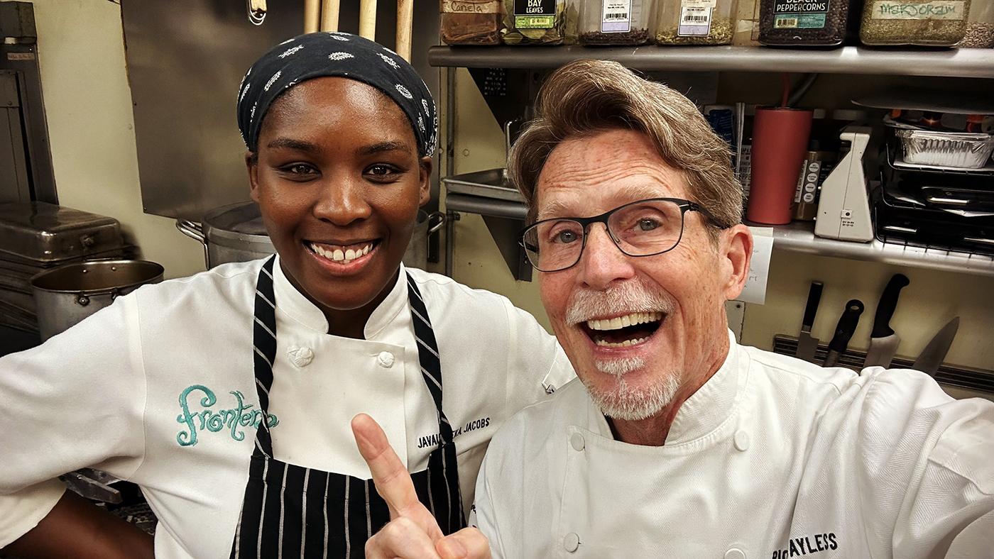 Chefs Javauneeka Jacobs and Rick Bayless smile for a selfie in the kitchen