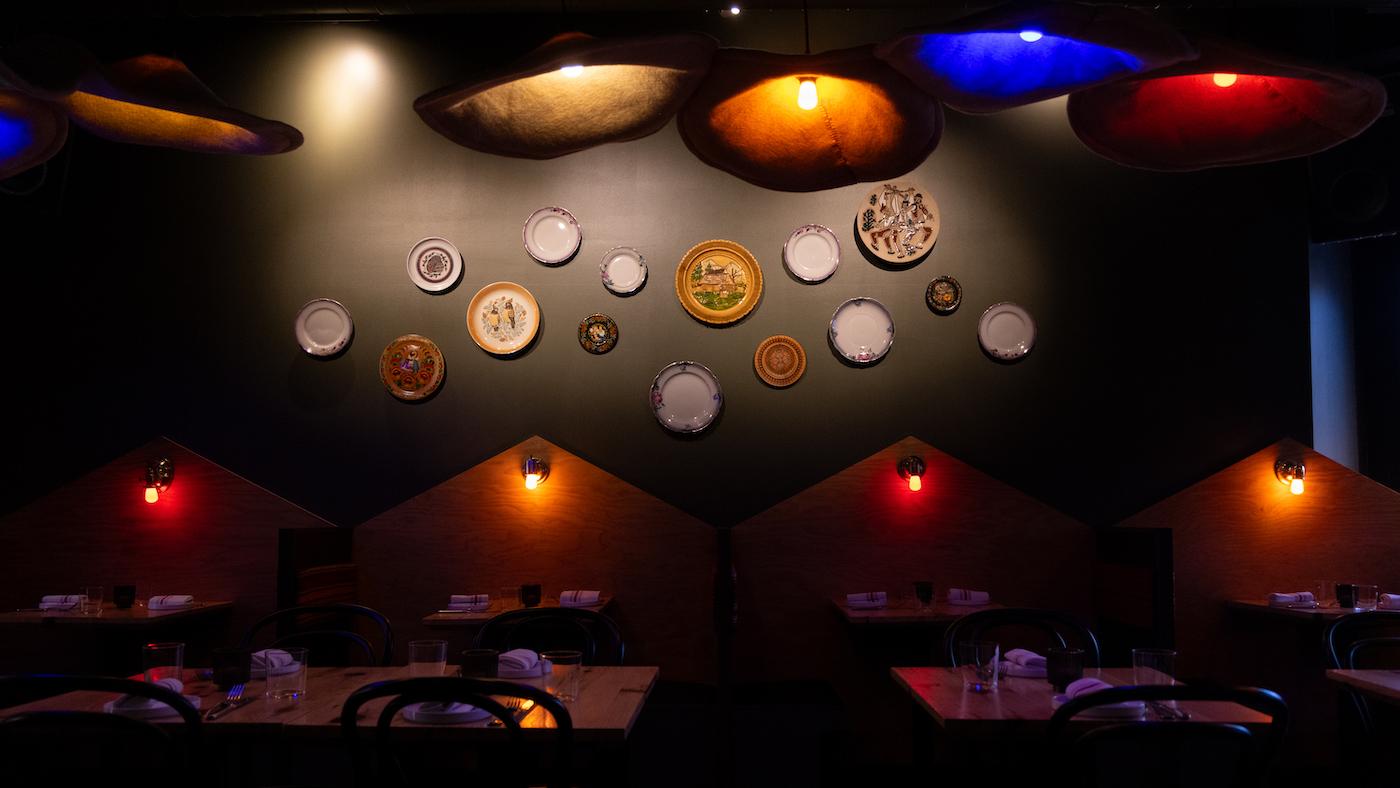 The dining room of Anelya, with decorative plates on a wall and darkly lit booths