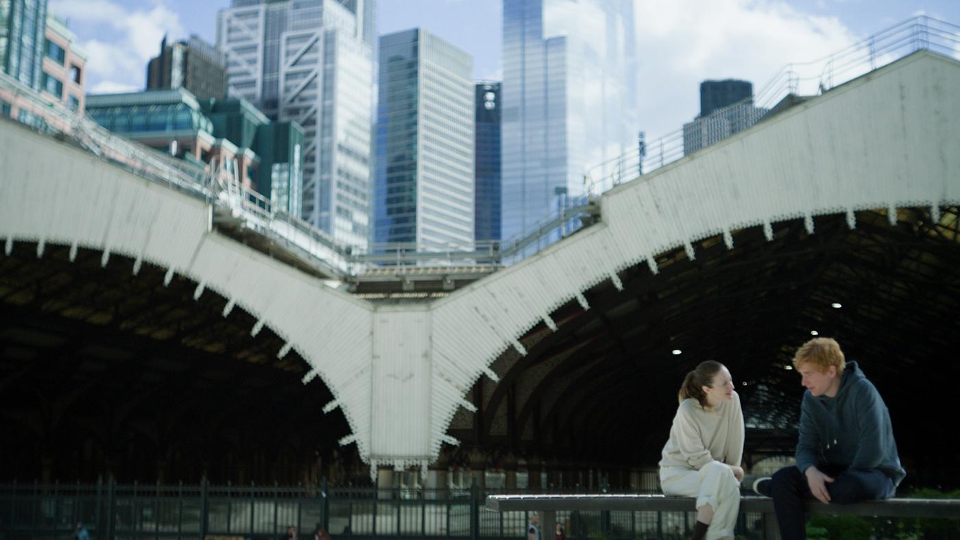 Alice and Jack sit in front of two large tunnels and some skyscrapers