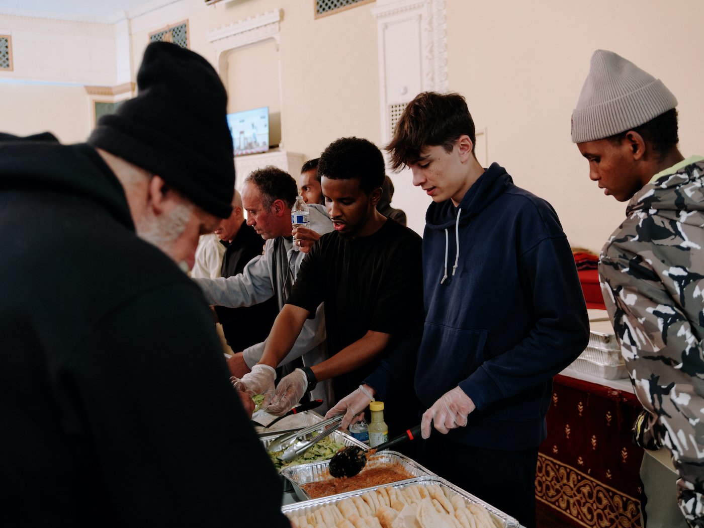 Young men stand behind a folding table and serve food from trays
