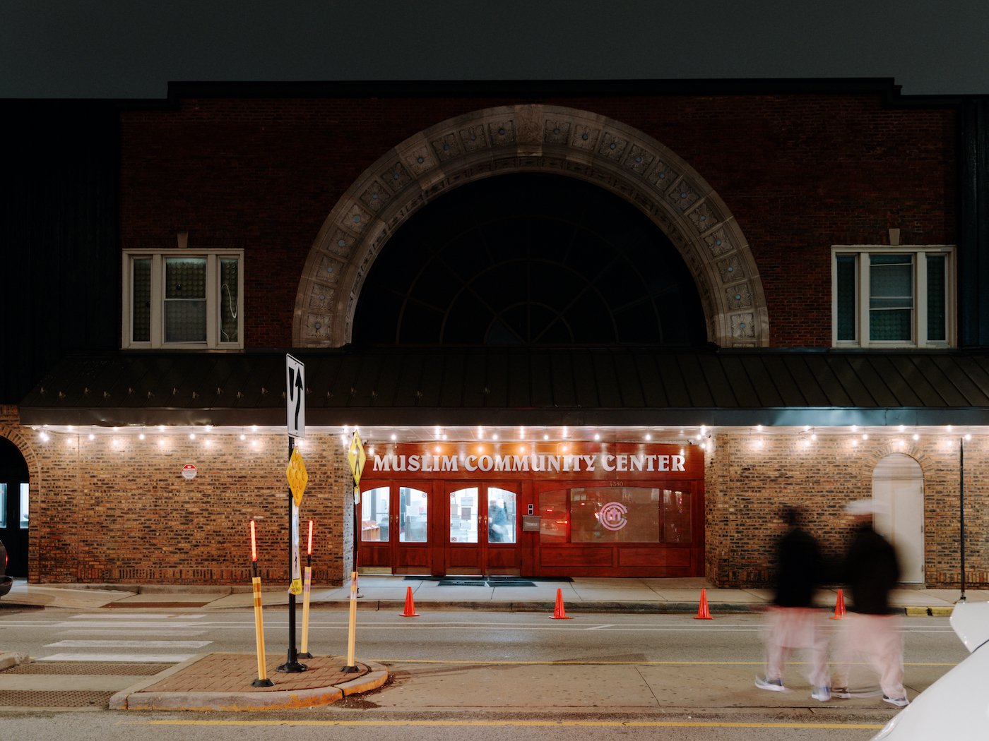 The arched exterior of the Muslim Community Center lit up at night