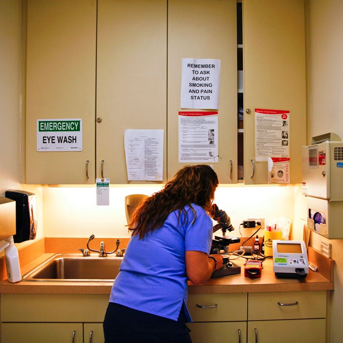 A nurse looks at samples on a microscope