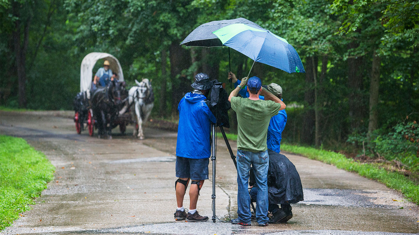 The camera crew braves the elements in Indiana to capture Geoffrey Baer and Joe Jarzen riding in a horse-drawn carriage along the National Road in July 2017