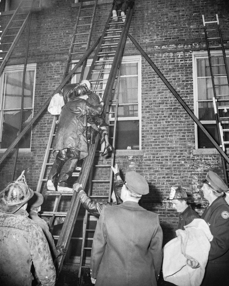 Firefighters carry a nun down a ladder