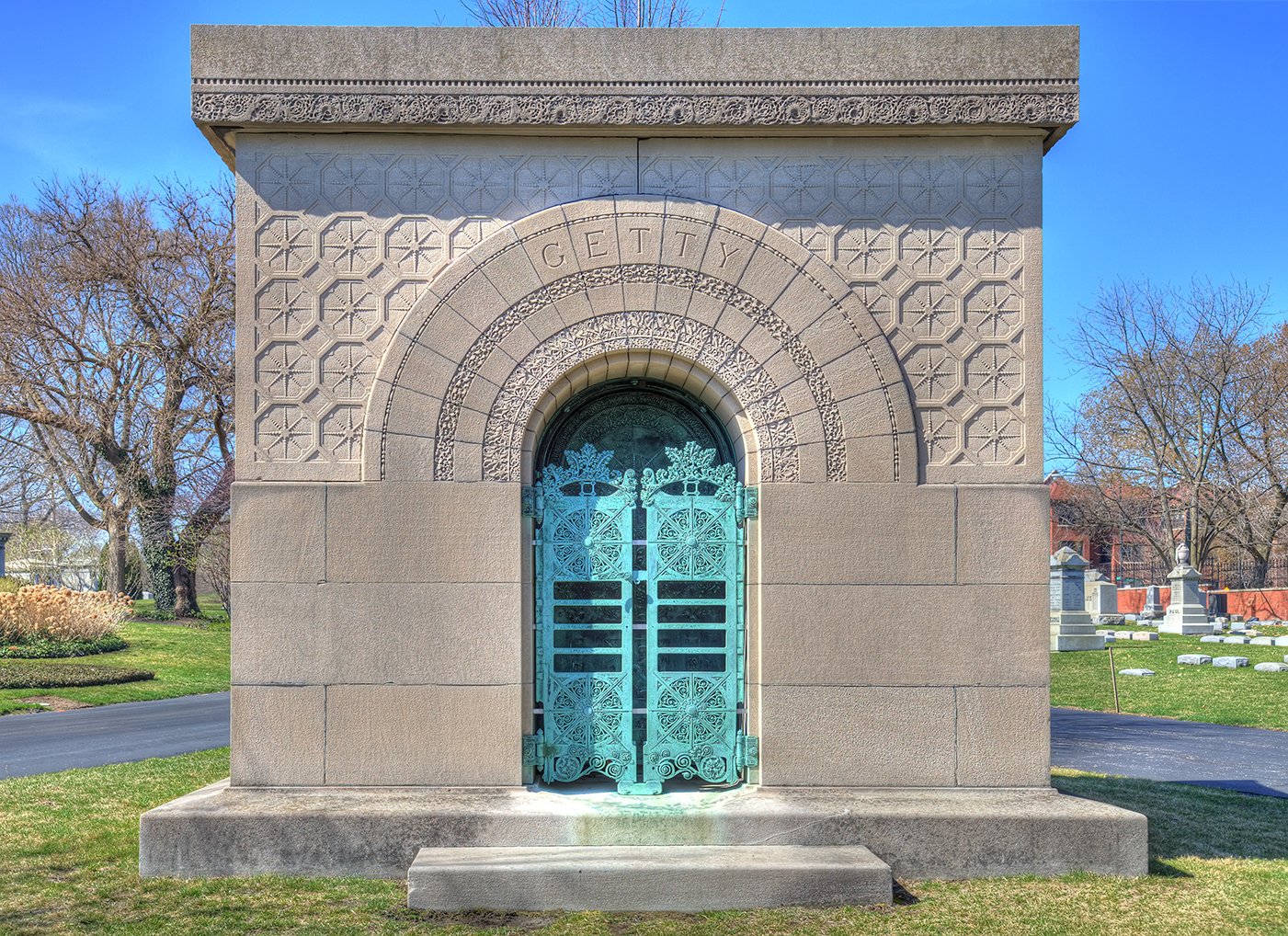 An ornate mausoleum with a green copper door