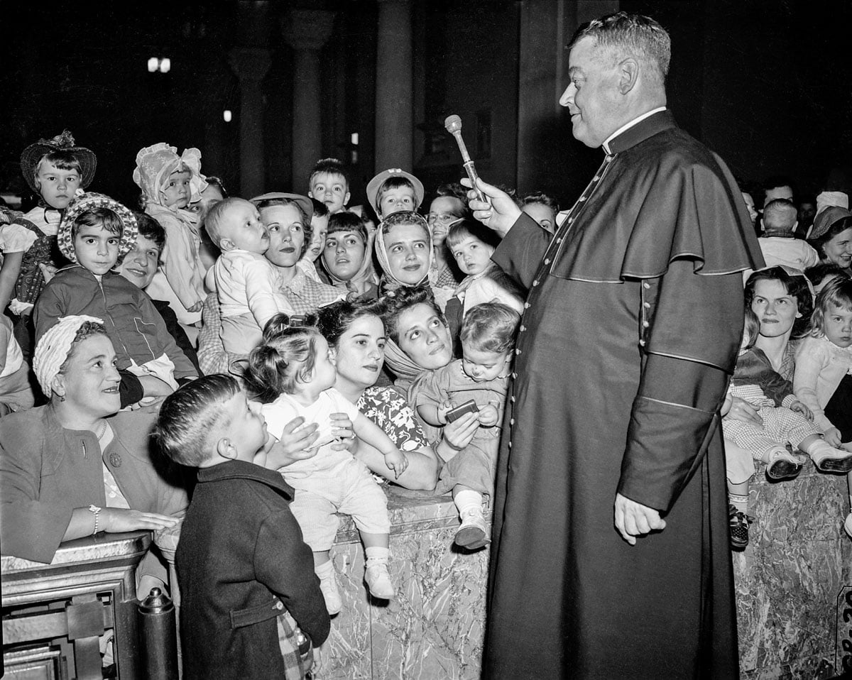 Monsignor Joseph Cussen, a pastor at Our Lady of the Angels, blesses children in 1954
