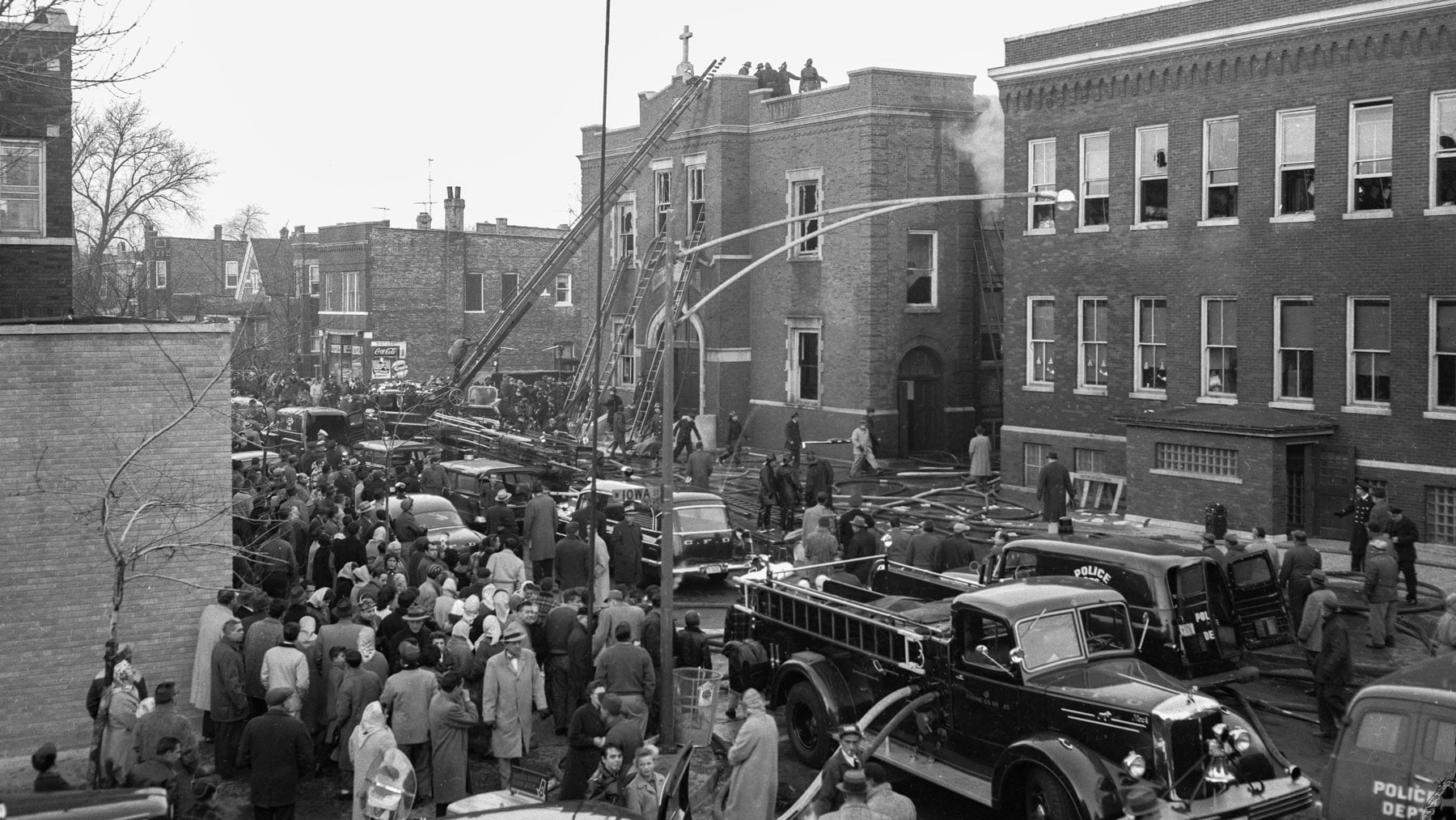 Historical photo of aftermath of Our Lady of the Angels fire with fire trucks and a lot of people in the street