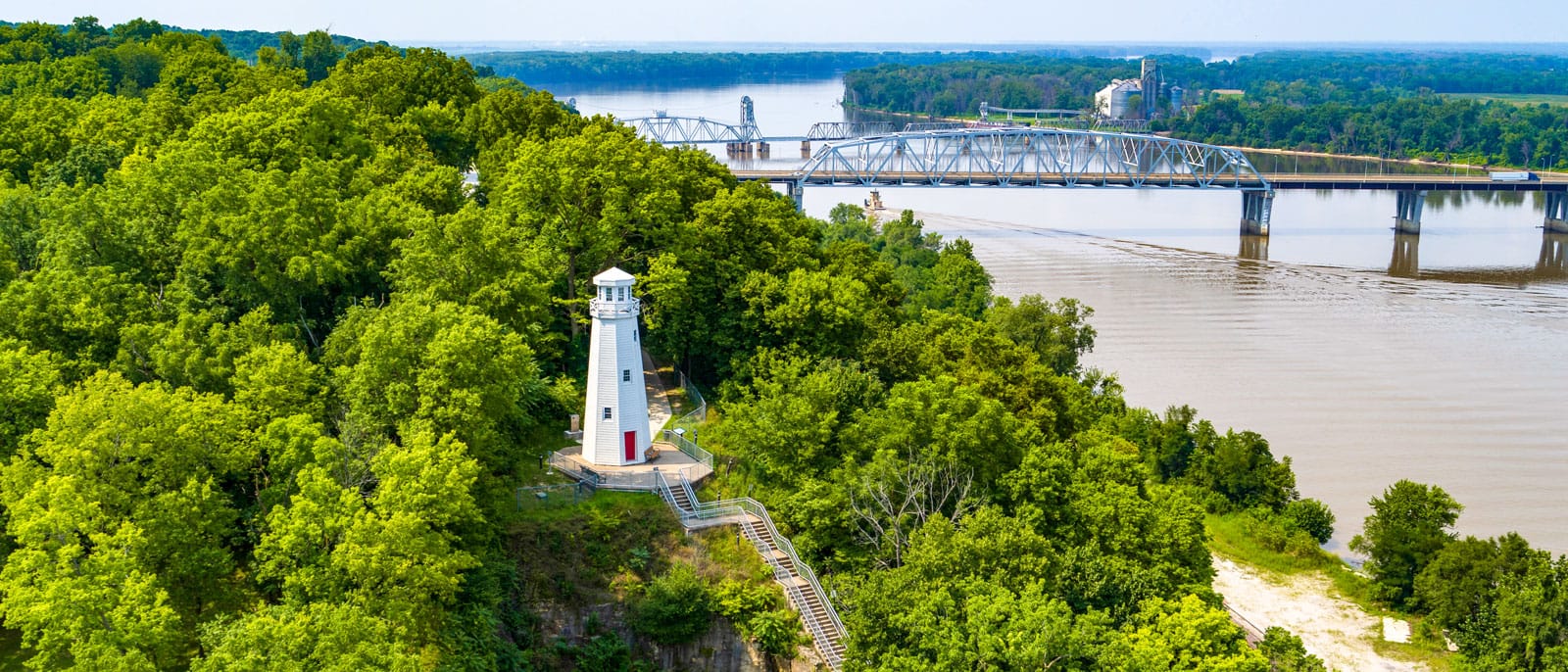 Lighthouse and trees on Mississippi River with bridge across river in background