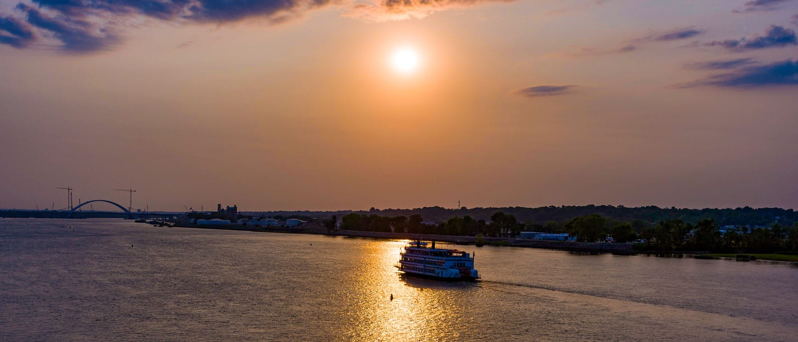 Boat on the Mississippi River with sun setting in background