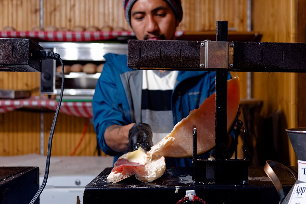 Christkindlmarket vendor making a raclette sandwich.