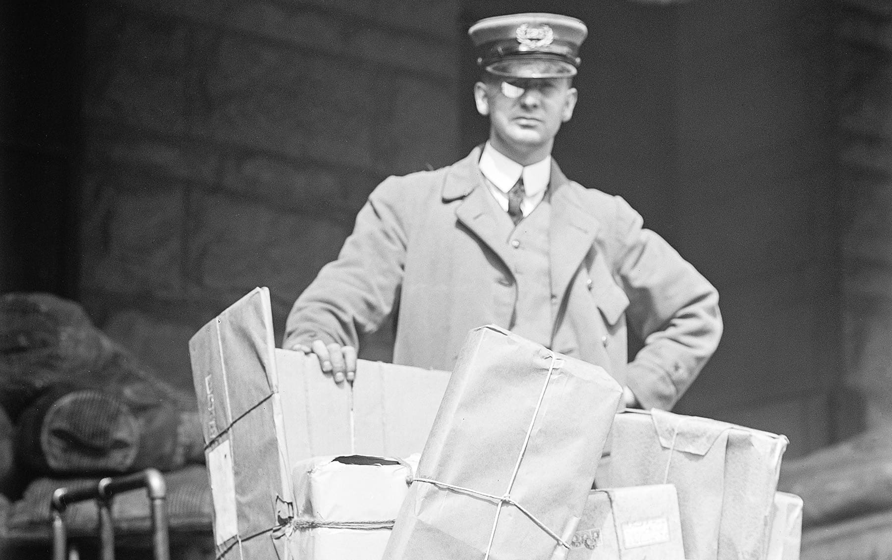 Postal worker standing behind a large wire basket of packages