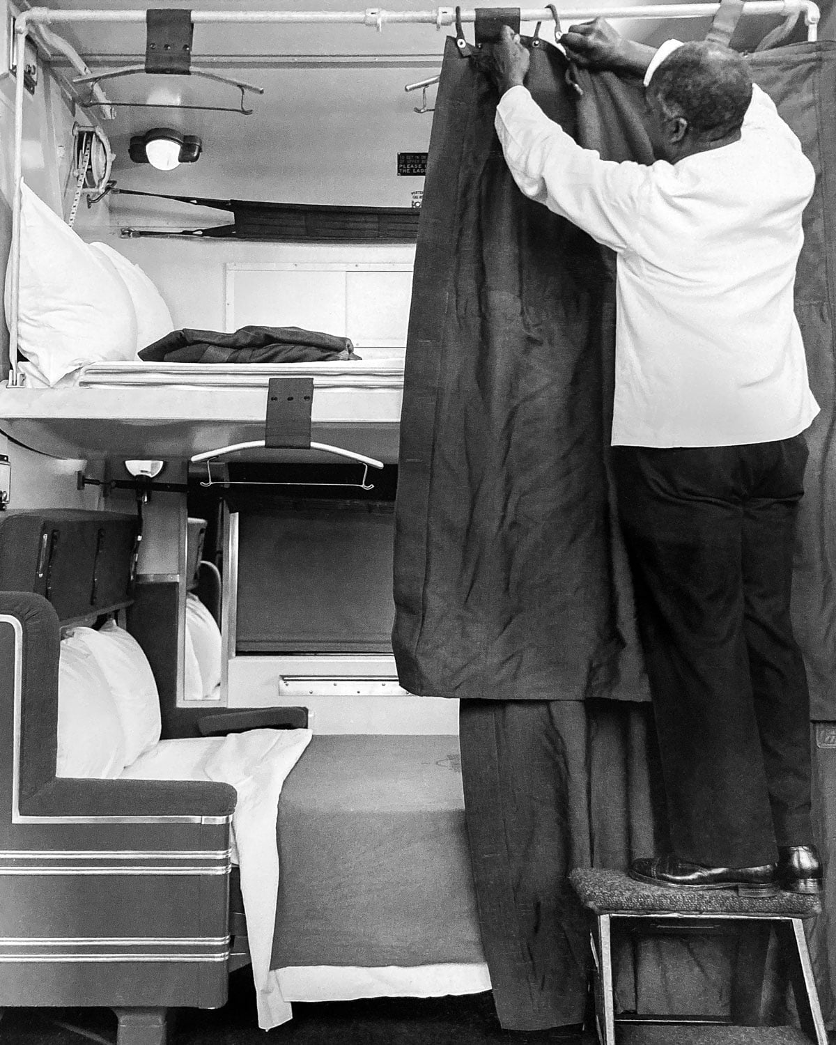 Porter hanging privacy curtain in train car