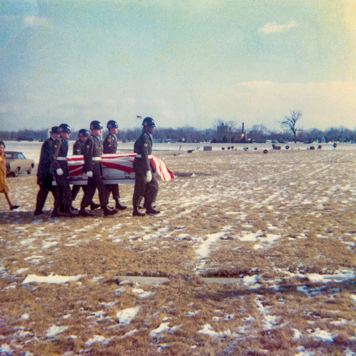 Soldiers carrying casket across field with snow
