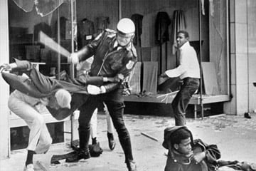 Several people around a police officer during a riot