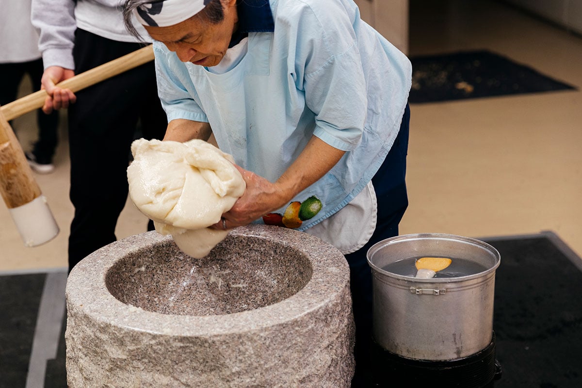 Mochi being taken out of the usu and coated in cornstarch
