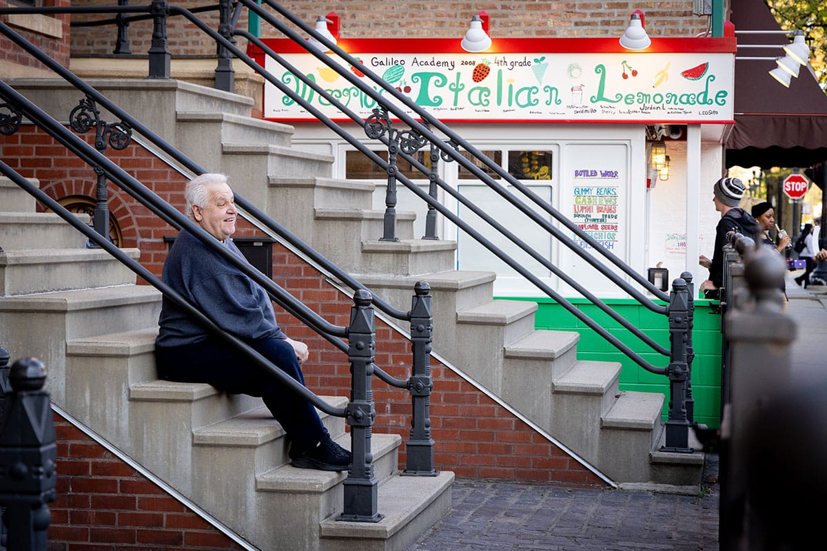 Mario DiPaolo sits on the stairs outside his store.