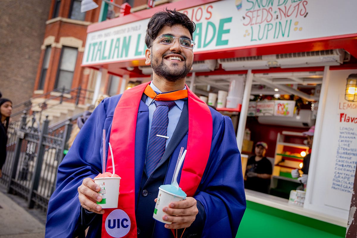 Akhil Nidadavolu in graduation gown holding two different flavors of Italian ice.