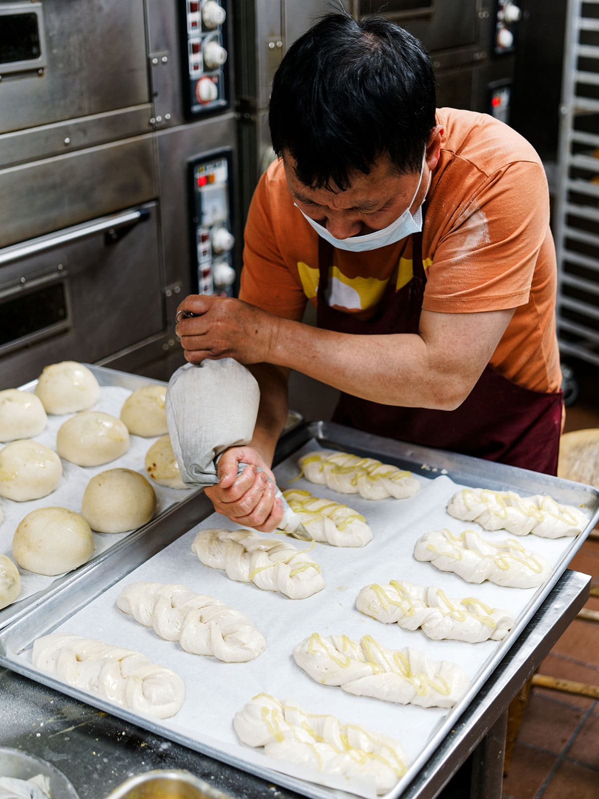 Baker piping a topping onto braided dough.