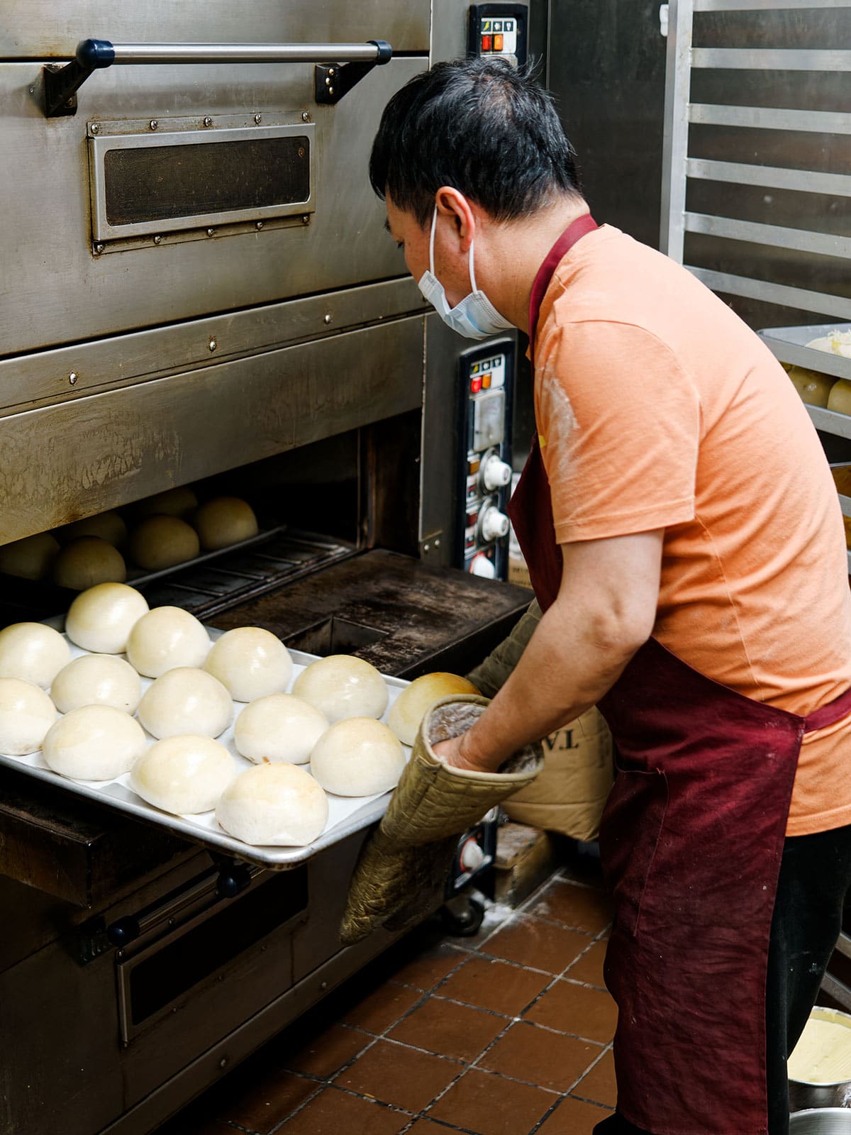 Baker puts a tray of BBQ pork buns into the oven.