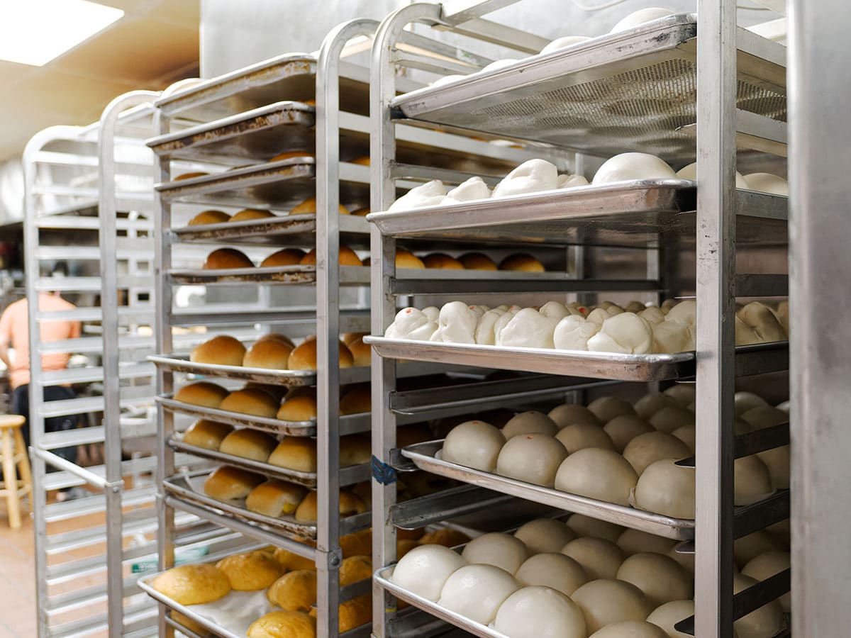 Trays of cooked breads cooling and unbaked loaves.