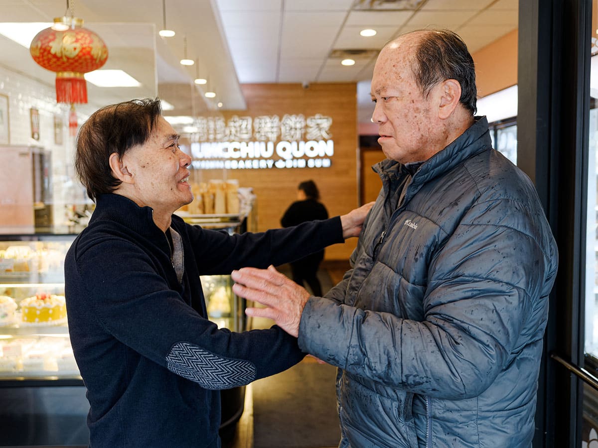 One of the owners of Chiu Quon shaking hands with a patron inside the bakery store.