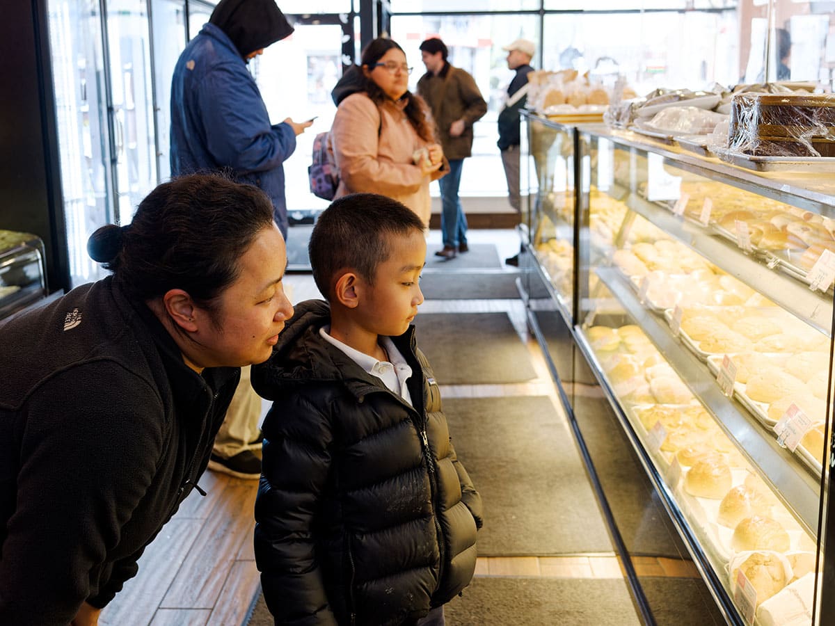 Mother and son looking at baked items in the display case.
