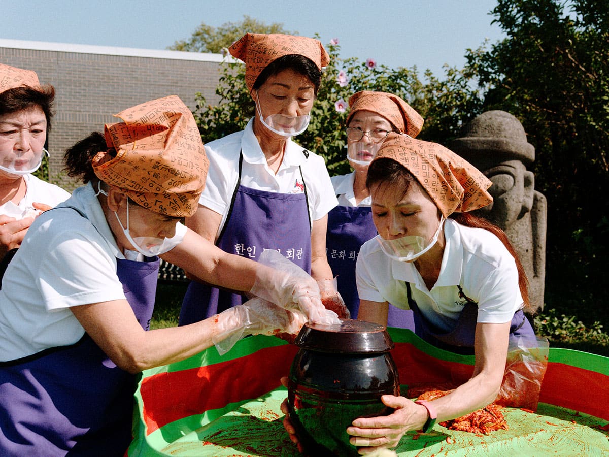 Women finish a container of kimchi and place the lid on top
