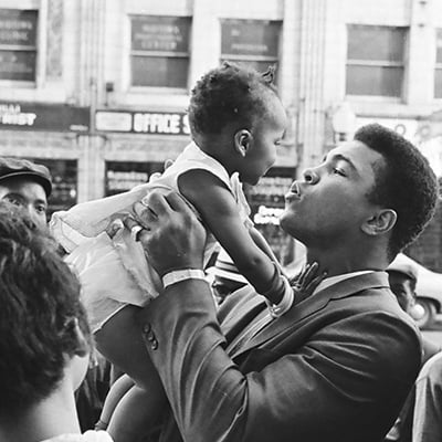 Muhammad Ali holds up a baby outside the Senate Theater located at 3128 West Madison Street, Chicago, Illinois, during a ceremony to donate items to starving families in Mississippi on July 24, 1967. Photo: ST-50000444-0004, Chicago Sun-Times collection, Chicago History Museum