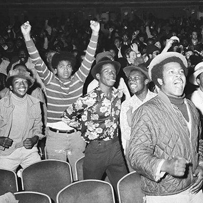 Fans cheer for Muhammad Ali as they watch his victory over George Foreman in Zaire. The fight was broadcast in a theater for fans to watch in Chicago, Illinois on October 29, 1974. Photo:   ST-20003241-0002, Chicago Sun-Times collection, Chicago History Museum