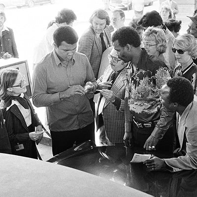 People stand around as Muhammad Ali signs autographs and pumps gas into his Rolls Royce in Chicago, Illinois on March 31, 1978. Photo: ST-19080061-0015, Chicago Sun-Times collection, Chicago History Museum