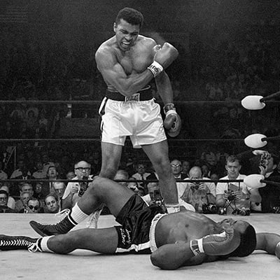 Muhammad Ali stands over fallen Sonny Liston, shouting and gesturing shortly after dropping Liston with a short hard right to the jaw in Lewiston, Maine. May 25, 1965. Photo: Courtesy of John Rooney/AP Images