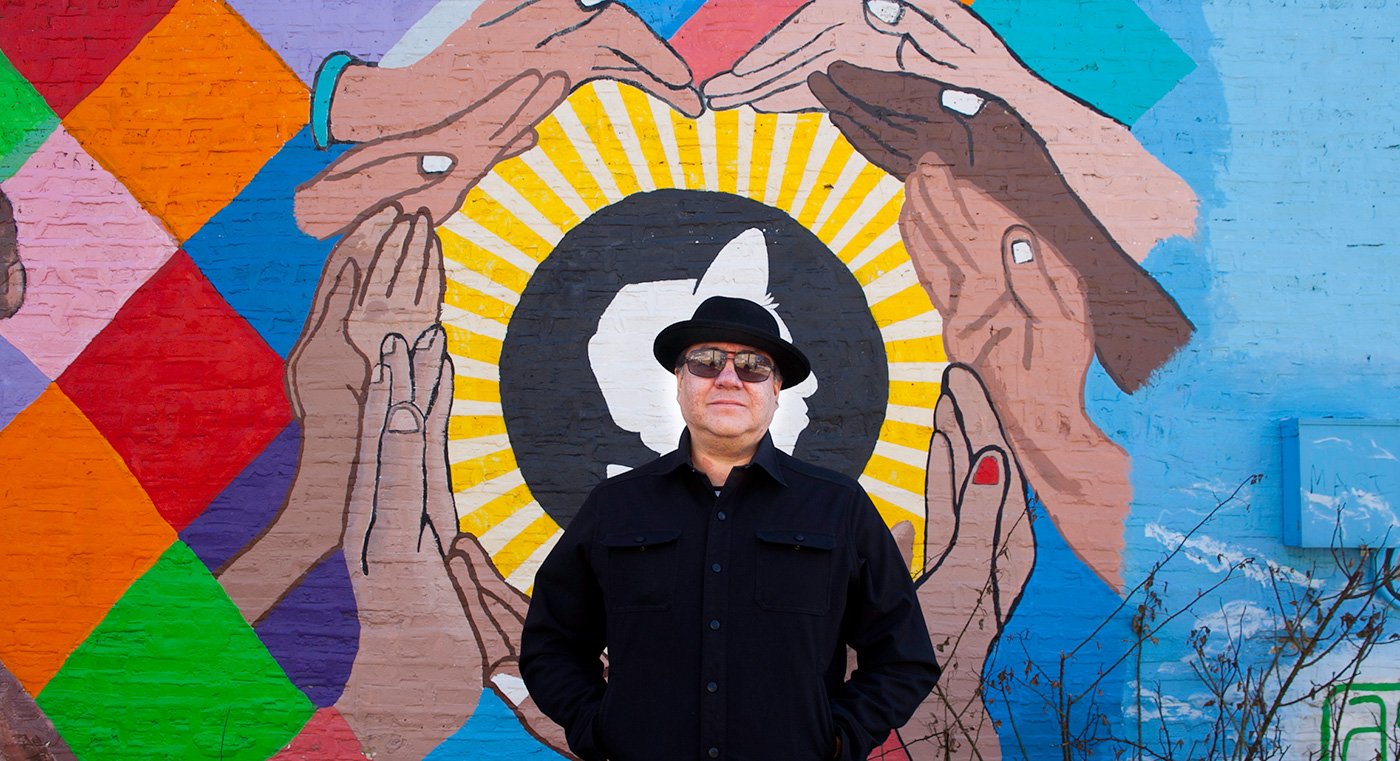 Jeff Maldonado stands in front of one of the many J-Def murals