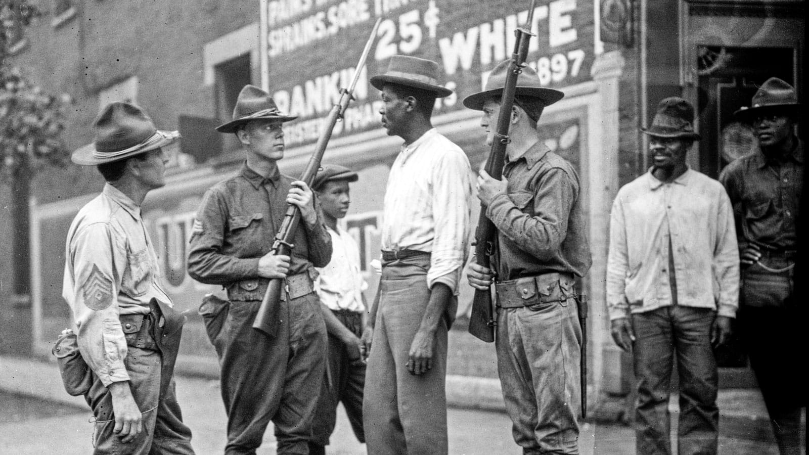 Armed National Guard and African American men standing on a sidewalk during the race riots in Chicago, Illinois, 1919