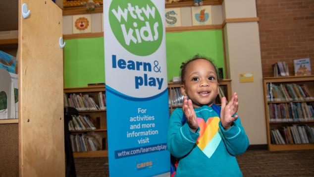 Young girl clapping in front of WTTW Kids Learn & Play banner