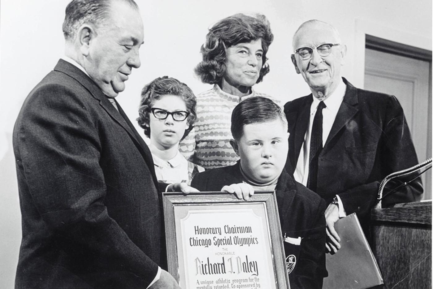 Pictured at the announcement proclaiming the Games, from left, Chicago Mayor Richard J. Daley; Joseph P. Kennedy, Jr. Foundation Executive Vice President Eunice Kennedy Shriver; and Chicago Park District President William McFetridge, alongside two young athletes
