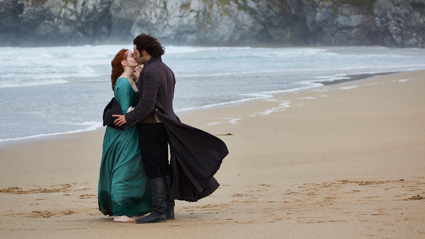Eleanor Tomlinson as Demelza kisses Aidan Turner as Ross Poldark on the beach. Photo: Mammoth Screen for BBC and MASTERPIECE