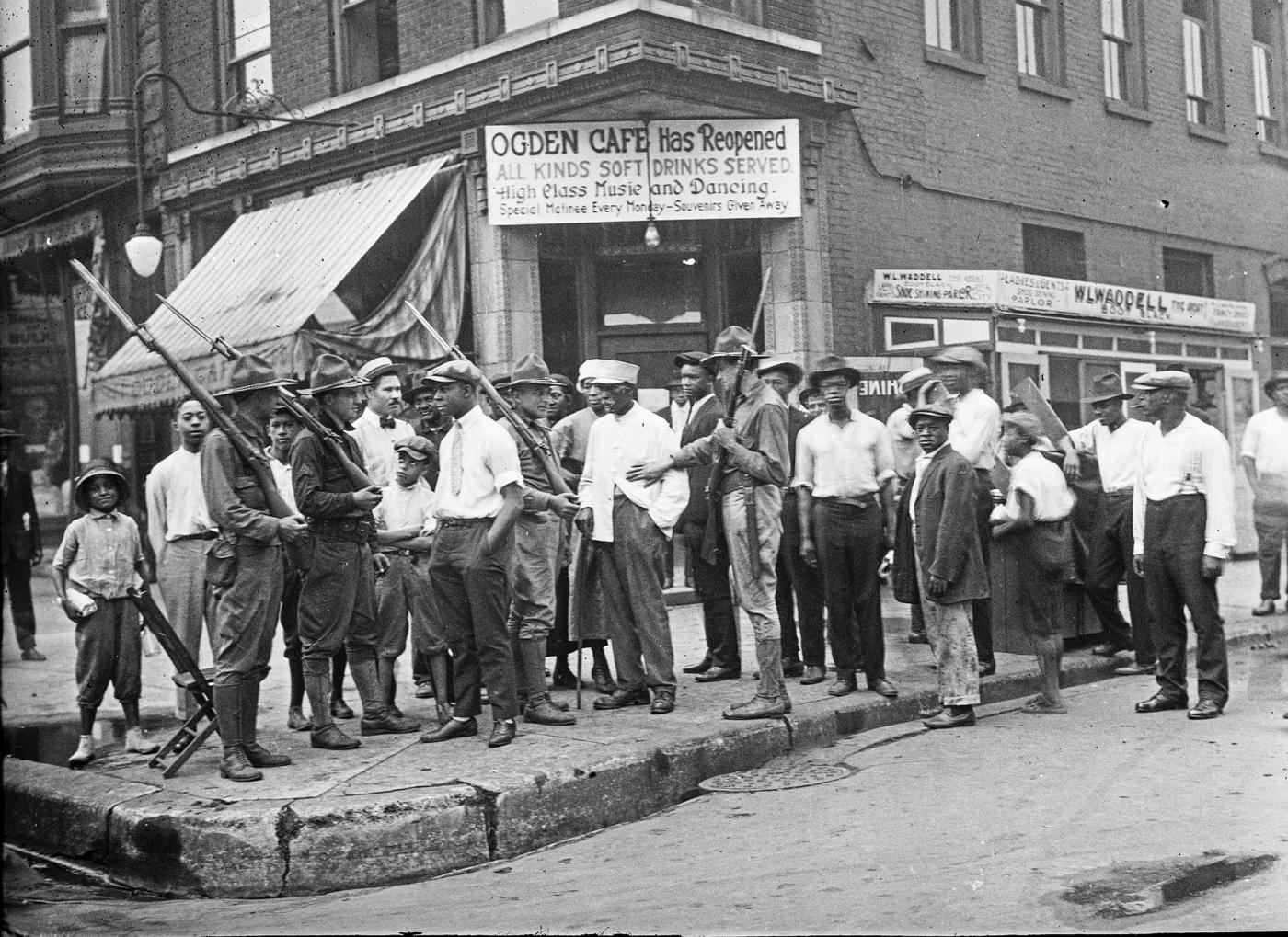 A crowd of men and armed National Guard stand in front of the Ogden Cafe during the 1919 race riot in Chicago.Photo: Chicago History Museum / The Jun Fujita negatives collection