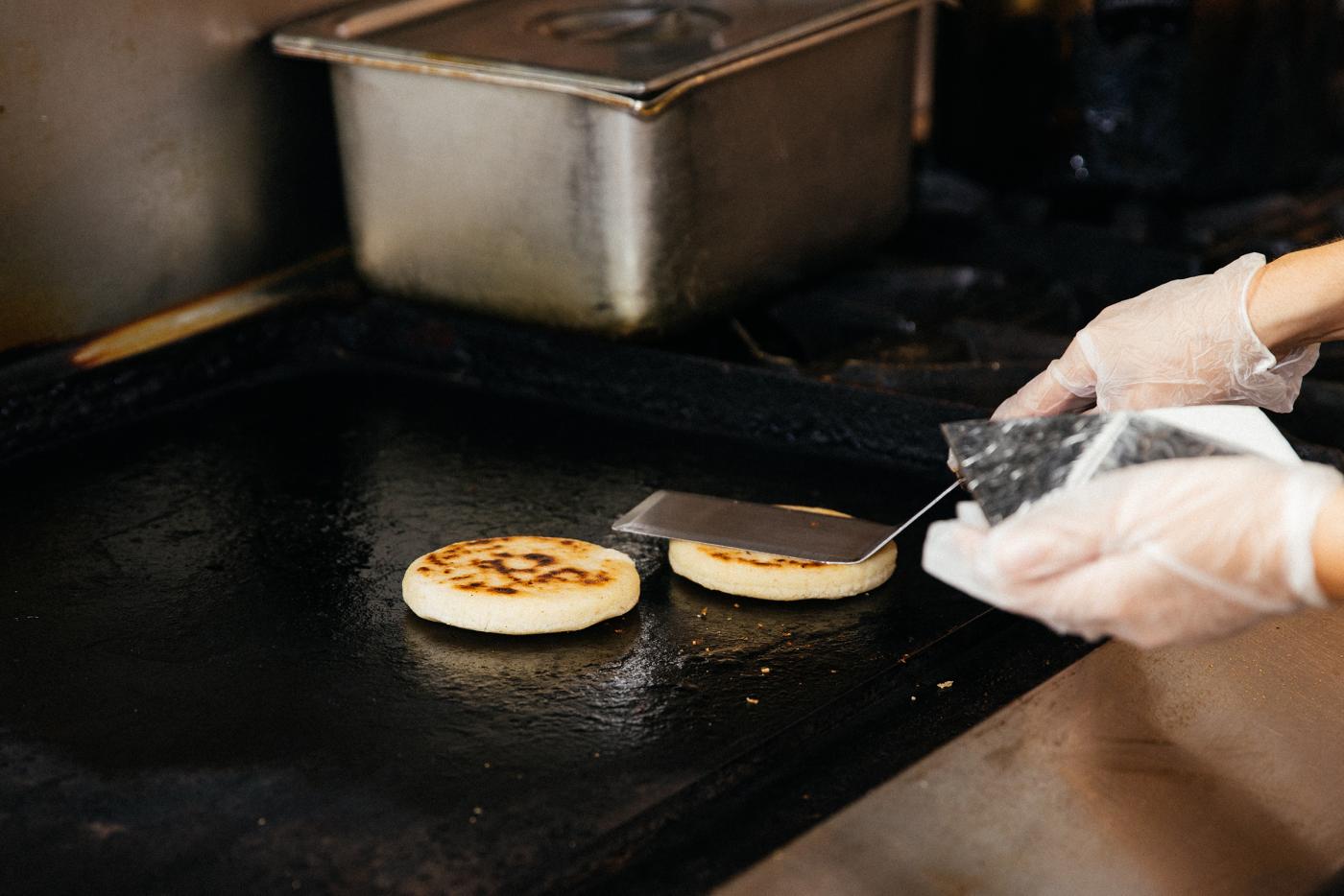 Andrea Andrade cooking arepas on the griddle at Sweet Pepper Venezuelan Food Bar. Photo: Sandy Noto for WTTW