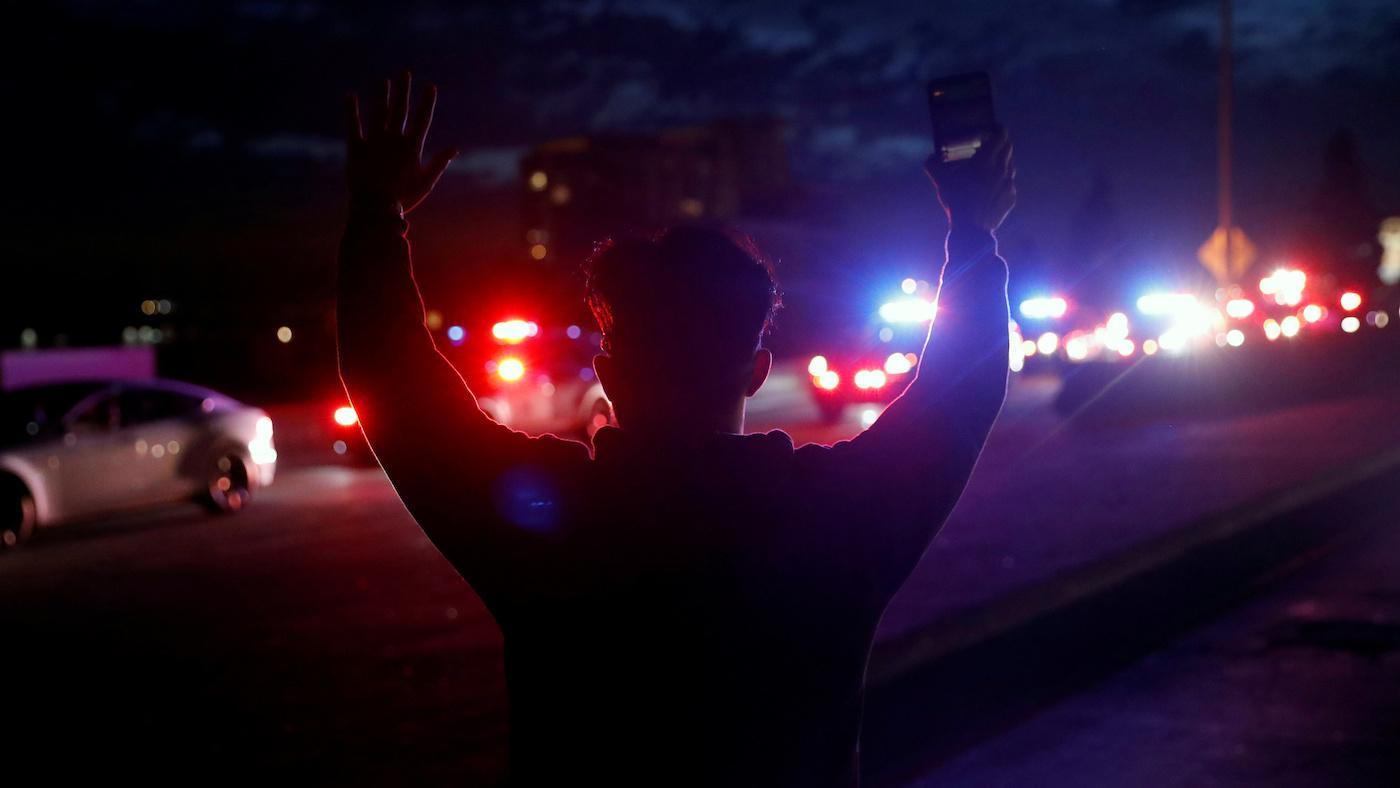 A demonstrator raises his arms towards a convoy of police vehicles during a protest in Oakland, California in May 2020 after the death of George Floyd. Photo: Stephen Lam/REUTERS