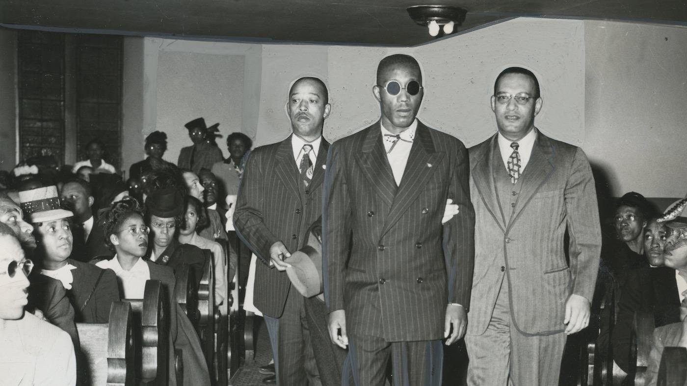Leroy Carter (left) and Donald Jones, NAACP assistant field secretary (right), escort Sergeant Isaac Woodard (center) down an aisle, October 26, 1946. Image: Courtesy of the AFRO American Newspapers Archives